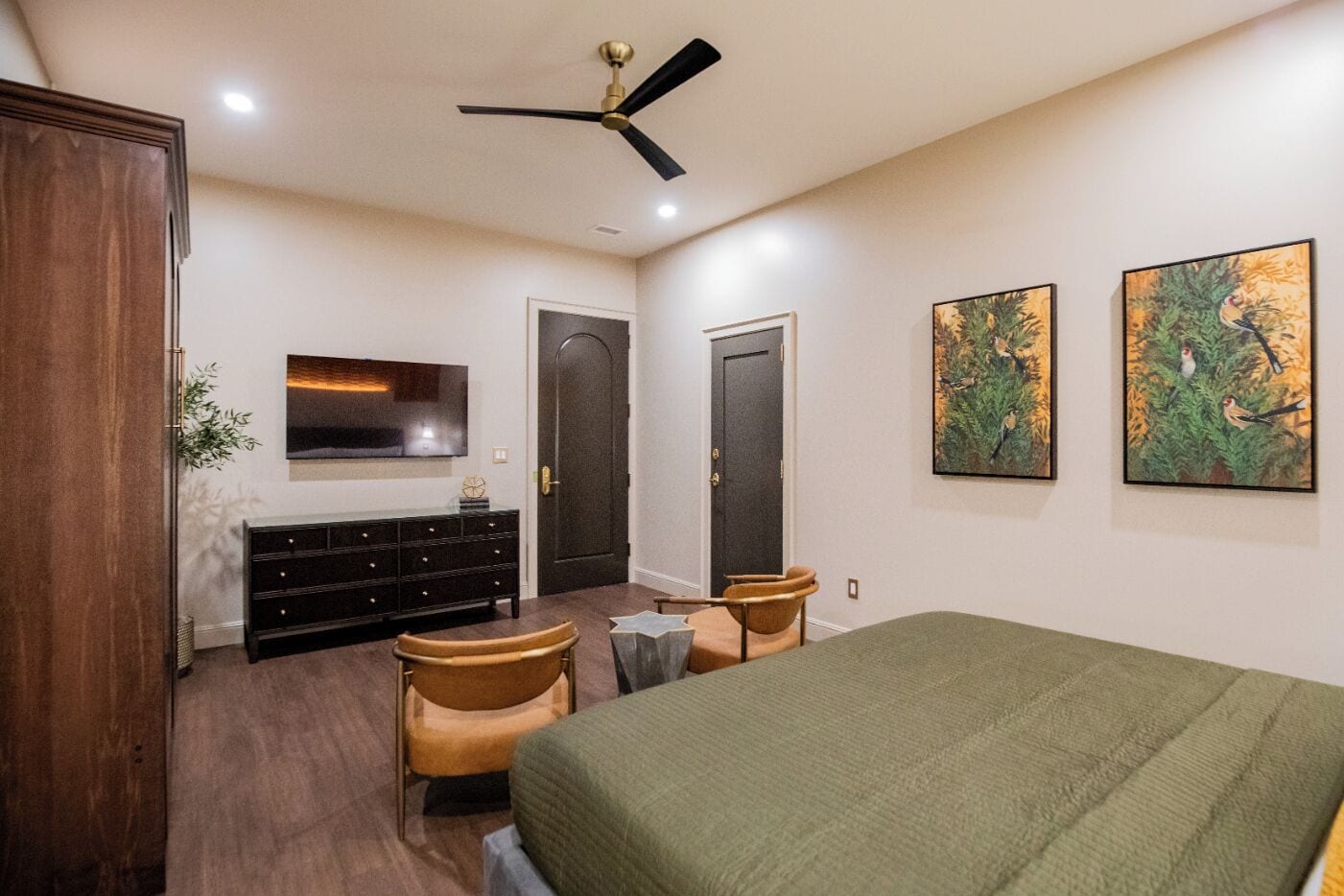 Une chambre à coucher avec un lit, une télévision, une commode, une chaise et deux portes.