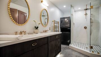 Un baño moderno con un tocador grande, dos espejos, una ducha y lavadora y secadora integradas.