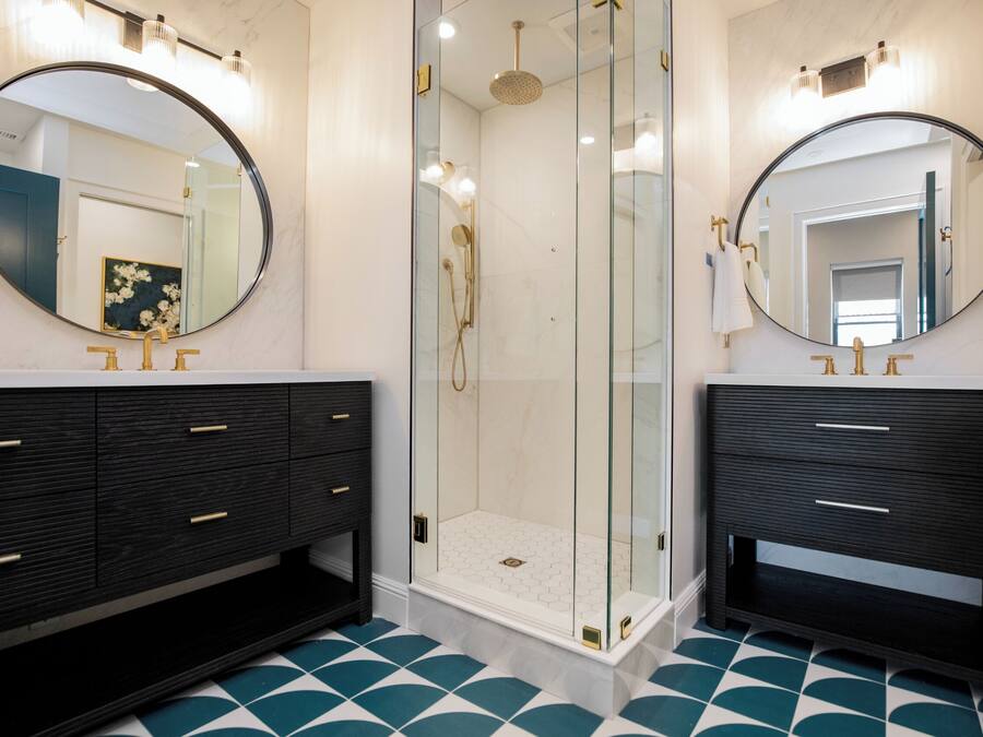 A bathroom with two dark wooden vanity units, a glass-enclosed shower, and a tiled floor.