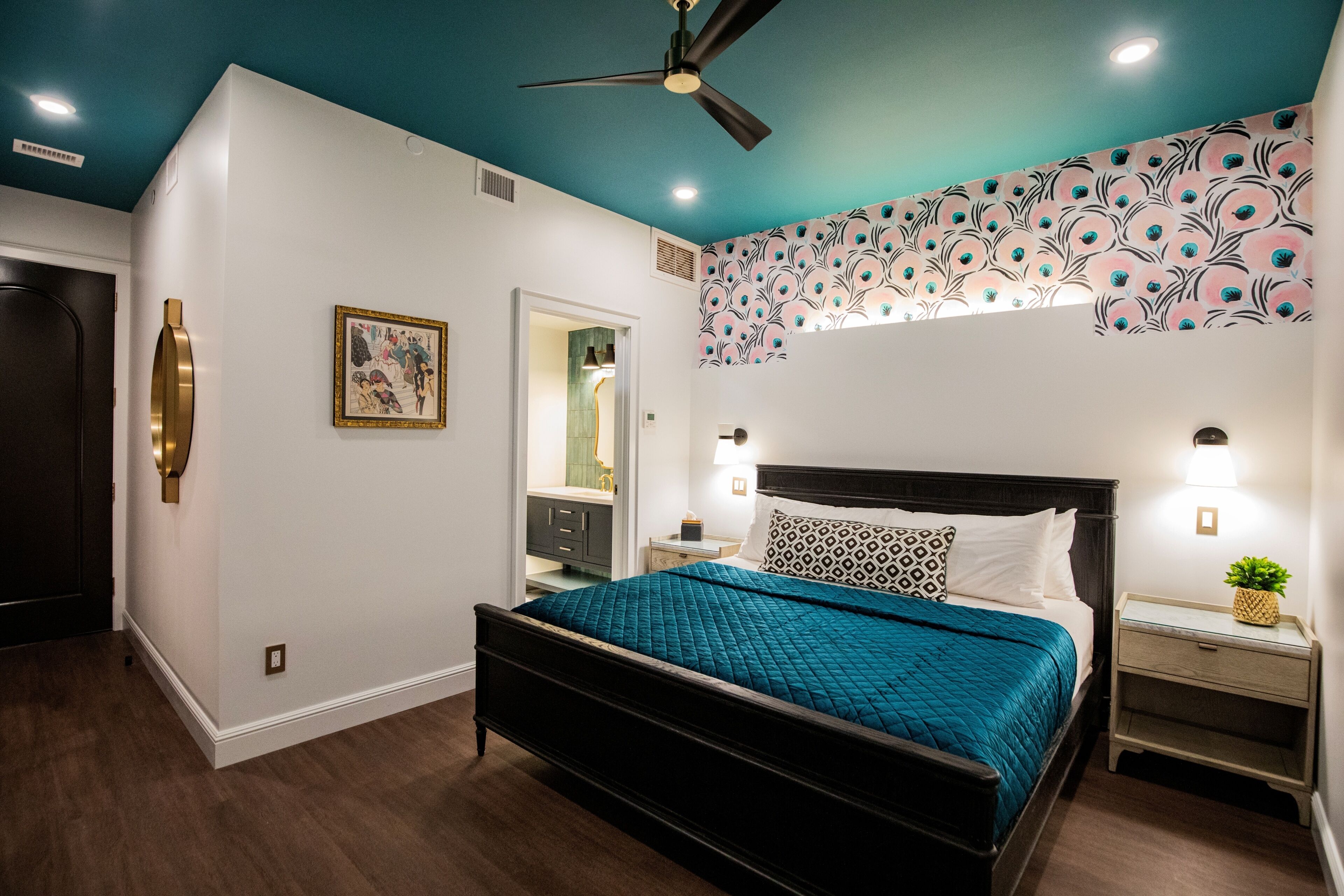 A bedroom with a bed, bedside tables, a ceiling fan, and a wall with a floral pattern.