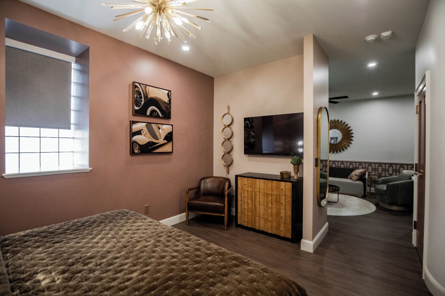 A modern bedroom with a large bed, a desk with a chair, a TV, and artwork on the walls.