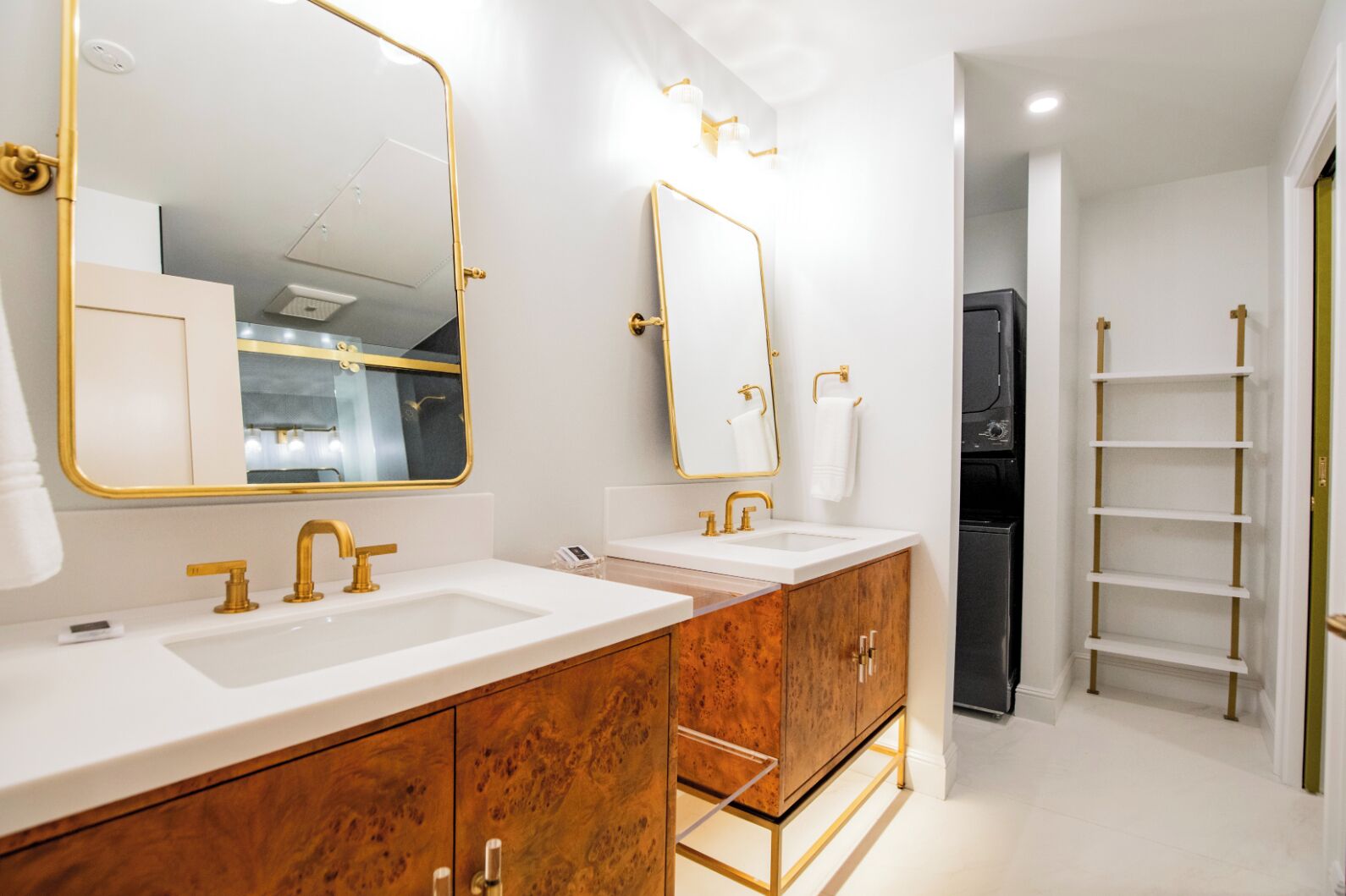 Une salle de bain moderne avec deux vasques, des robinetteries dorées et une coiffeuse avec un grand miroir.
