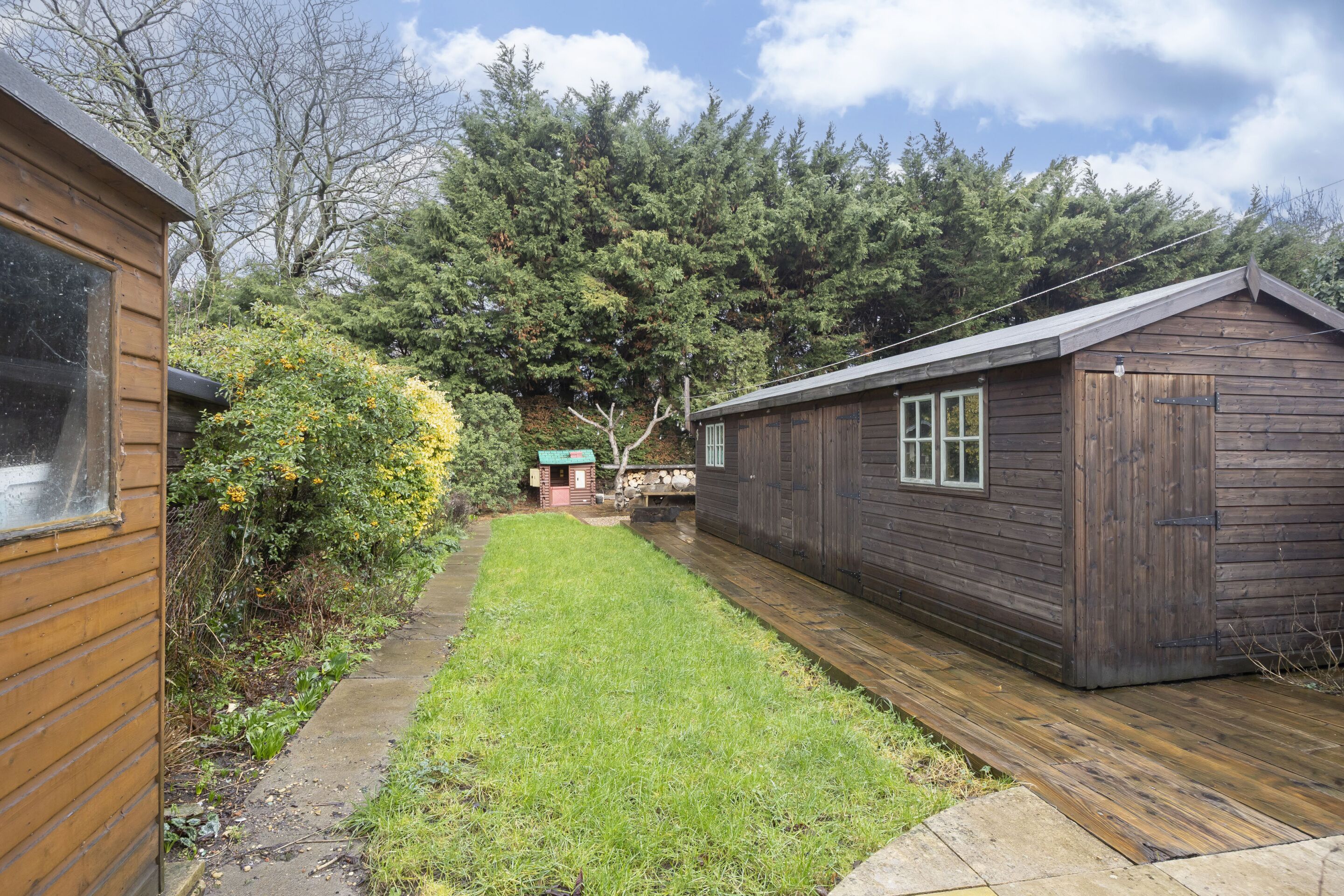 A wooden cabin with a small deck and a grassy yard.