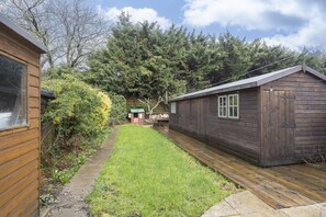 Une cabane en bois avec une petite terrasse et une cour gazonnée.