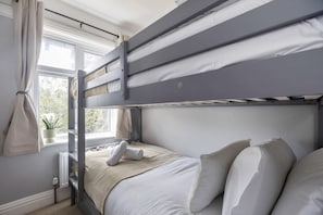 A bunk bed with a window view, a radiator, and a potted plant.