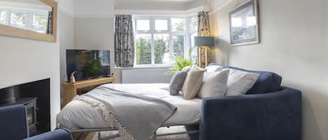 Un dormitorio moderno con cama, televisor, escritorio y ventana con cortinas.