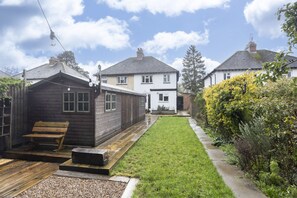 A residential area with a wooden cabin, a white house, and a well-maintained lawn. - Lovely 2-Bed Home right by Cheltenham Race Course (Cheltenham)