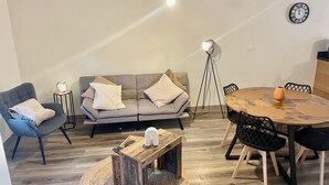 A modern living room with a grey sofa, a round wooden table, and a coffee table.