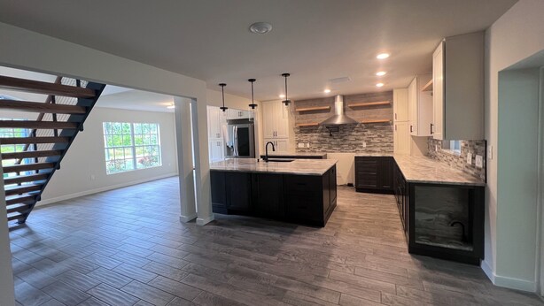 A spacious kitchen with a central island, dark cabinetry, and a modern backsplash. - Spacious 5-bedroom Pool Home near Beaches-Hot Tub, Kayaks, Massage Chair (North Port)