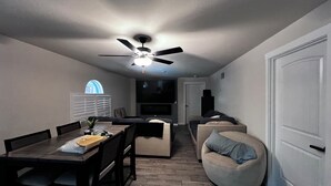 A compact living space with a dining area, a sofa, and a ceiling fan. - Spacious 5-bedroom Pool Home near Beaches-Hot Tub, Kayaks, Massage Chair (North Port)