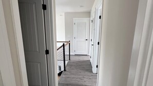 A hallway with a wooden floor, white walls, and doors leading to other rooms. - Spacious 5-bedroom Pool Home near Beaches-Hot Tub, Kayaks, Massage Chair (North Port)