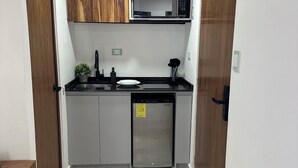 Una cocina compacta con microondas integrado, lavavajillas y armarios de madera.