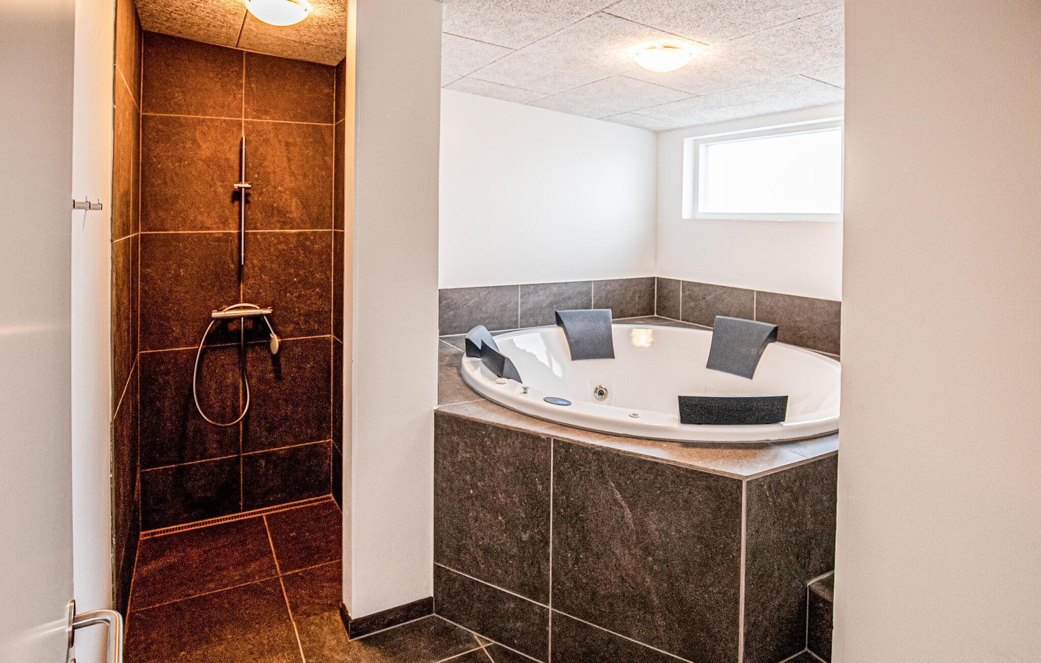 Ein modernes Badezimmer mit bodengleicher Dusche, freistehender Badewanne und einem Fenster für natürliches Licht.