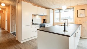 A modern kitchen with white cabinetry, a central island, and a window providing natural light. - Gorgeous home in Grenaa with sauna (Grenaa)