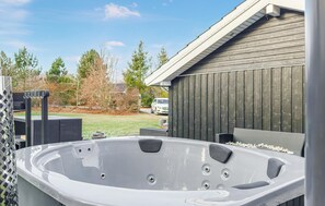 Ett bubbelbad i en trädgård, med ett staket av trä och en bil synlig i bakgrunden.