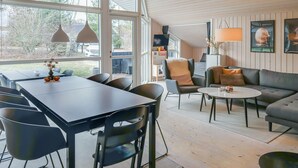 Un salon moderne avec un coin repas, de grandes fenêtres et un espace salon confortable.