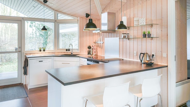 Une cuisine moderne dotée d’un grand îlot central, de tabourets de bar blancs et de panneaux en bois.