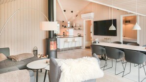 Un salon chaleureux avec une cheminée, un coin repas et une cuisine équipée d’un grand téléviseur.