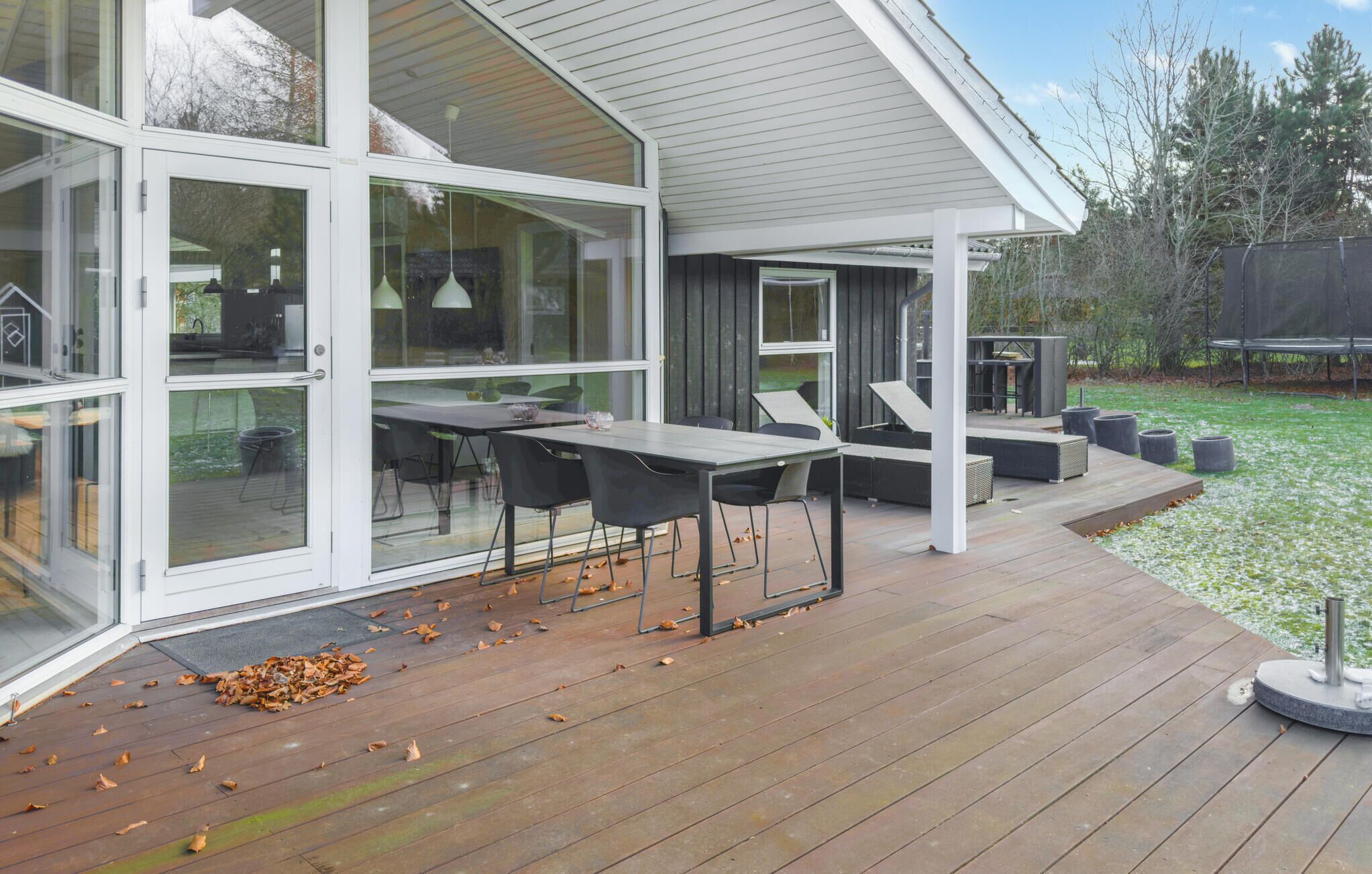 A modern house with a deck, large glass doors, and outdoor furniture.