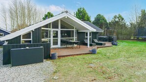 Une maison moderne dotée d’une grande terrasse, d’un espace salon extérieur et d’un patio couvert.