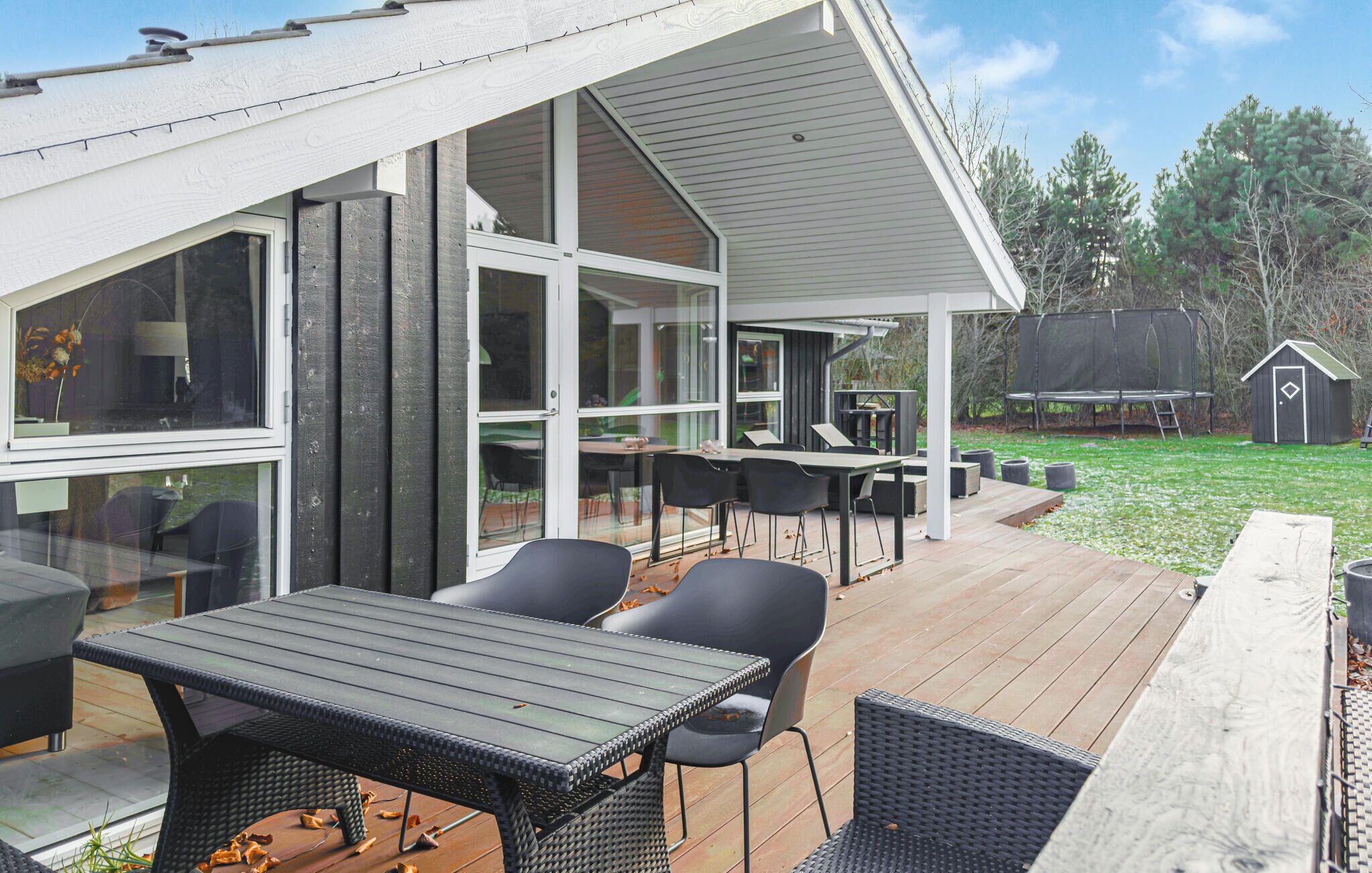 A covered outdoor patio with a dining area, including tables and chairs, and a view of the surrounding landscape.