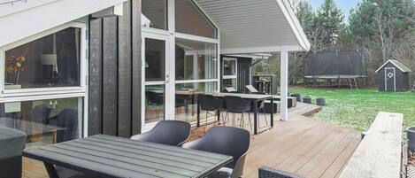 A covered outdoor patio with a dining area, including tables and chairs, and a view of the surrounding landscape.