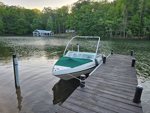 A boat docked at a wooden pier with a house in the background.