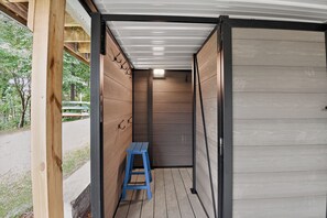 Un espace extérieur abrité, doté d’un banc en bois, d’une porte et offrant une vue sur l’extérieur.