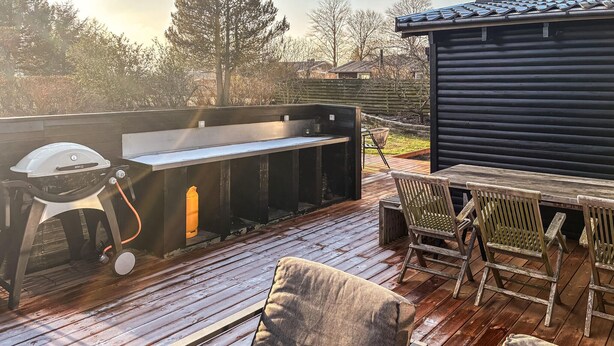 Eine Terrassenausstattung im Freien mit Grill, Tisch und zwei Stühlen.