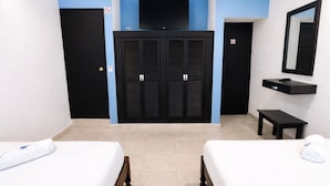 Ein Hotelzimmer mit zwei Betten, einem Fernseher, einem Kleiderschrank und einem kleinen Tisch.