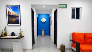 Eine Hotelhalle mit einer Rezeption, einer Uhr, einer blauen Tür und einem orangefarbenen Sofa.
