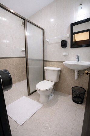 Une salle de bain équipée de toilettes, d’un lavabo, d’un sèche-mains et d’une poubelle.