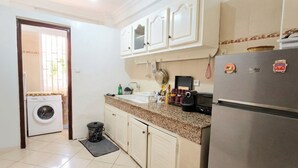 Une cuisine équipée d’un lave-linge, d’un réfrigérateur et d’un four à micro-ondes.