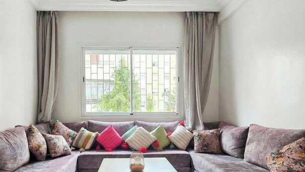Un salon avec un canapé, une fenêtre et des rideaux.