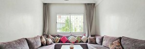 Una sala de estar con sofá, ventana y cortinas.