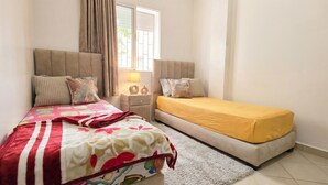 Une chambre à coucher avec un lit, une table de chevet, une lampe et une fenêtre.