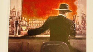 A bar with a man in a suit and hat, a martini glass, and bottles in the background. - The Luxe Loft Apartment. (Wolverhampton)