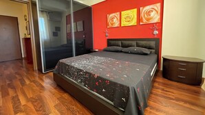 Ein Schlafzimmer mit einem großen Bett, einem Schiebetürenschrank und einer roten Wand mit floralen Bildern.