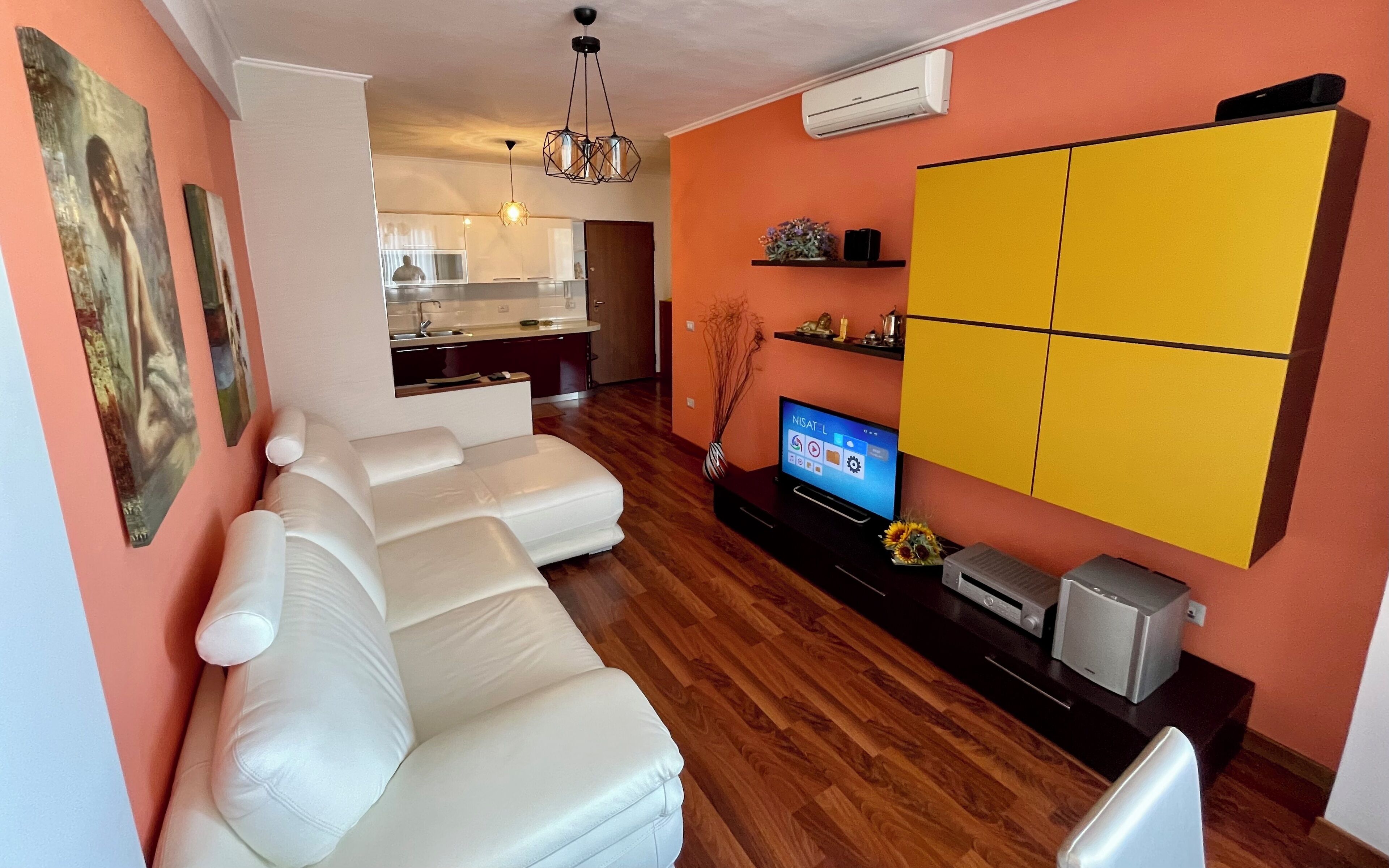 A modern living room with a white leather sofa, a flat-screen TV, and a yellow cabinet.