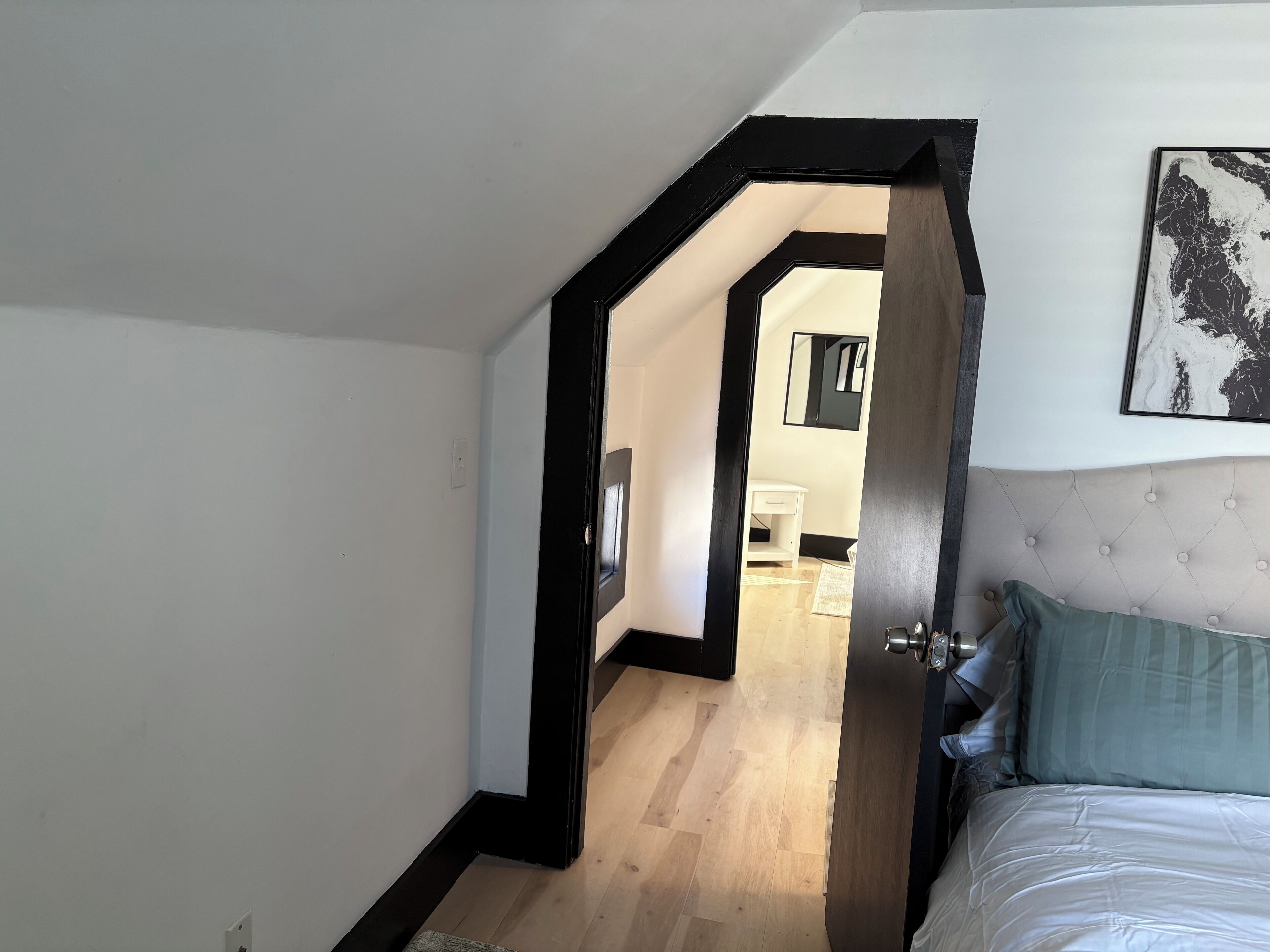 Une chambre à coucher avec un lit, une porte donnant sur une salle de bain et un couloir.