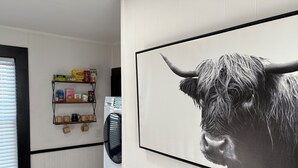 A room with a white wall, a mounted picture of a bull, a shelf with various items, and a window with blinds. - 2-Bedroom Home ~ Near Portsmouth/Durham ~ Private Driveway ~ Washer/Dryer (Dover)