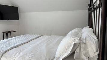 Ein ordentlich gemachtes Bett mit weißer Bettwäsche und einem hölzernen Kopfteil.