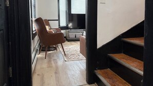 A modern living room with a brown leather chair, a flat-screen TV, and a staircase. - 2-Bedroom Home ~ Near Portsmouth/Durham ~ Private Driveway ~ Washer/Dryer (Dover)