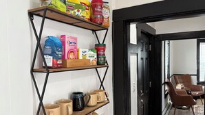 A kitchen with shelves holding various food items, a coffee maker, and mugs. - 2-Bedroom Home ~ Near Portsmouth/Durham ~ Private Driveway ~ Washer/Dryer (Dover)