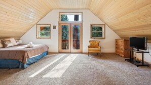 A bedroom with a sloped ceiling, a bed, a chair, a dresser, and a television. - Mountain Paradise- Family Cabin w Pool Table (Shaver Lake)