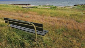 Un banc situé dans un espace verdoyant, offrant une vue sur la mer et un ciel nuageux.