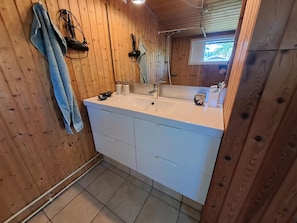 A wooden-paneled bathroom with a white sink, two drawers, a towel, and a mirror. - Nature, peace and coziness near forest and beach (Nakskov)
