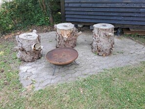 Un jardín con una zona de estar circular y tres taburetes hechos con troncos de árbol.