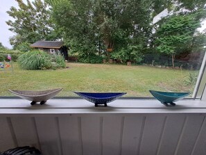 Un alféizar con tres cuencos decorativos y vistas a una casa y jardín.