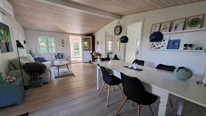 Amplia sala de estar con una mesa de comedor, sillas y un sofá. Se observa una cocina al fondo.
